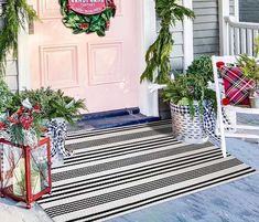 a front porch decorated for christmas with wreaths and potted plants