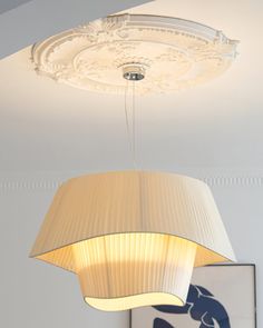 a light fixture hanging from the ceiling in a room with a painting on the wall