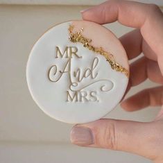 a hand holding a cookie with the words mr and mrs on it in gold glitters