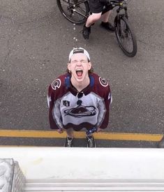 a man with his mouth open standing in front of a bicycle and another person on the ground