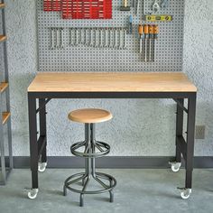 a workbench with tools hanging on the wall and two stools in front of it