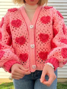 a woman wearing a pink crocheted cardigan with hearts on it