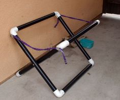 an upside down chair sitting on the ground next to a wall with purple string attached to it