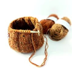 three balls of yarn are sitting next to each other on a white surface, one is brown and the other is orange