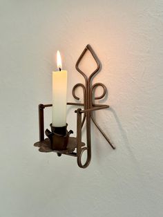 a candle that is sitting on a wall next to a cup holder with a spoon in it