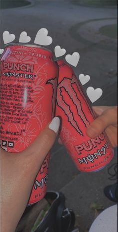 a person holding two cans of drink with hearts on the top and one is pink