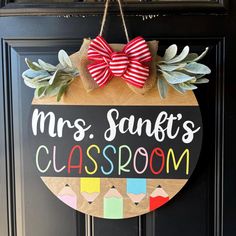 a wooden sign that says mrs santa's classroom hanging on a door with a bow