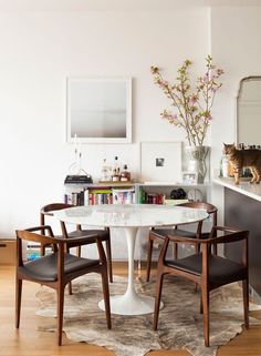 a dining room table with chairs and a cat on the wall in the back ground