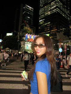 a woman wearing sunglasses and holding a cell phone in the middle of a crosswalk