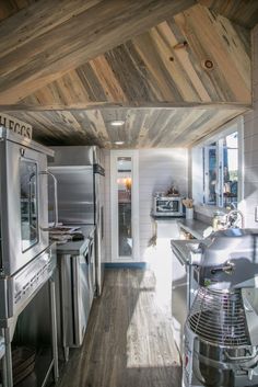 a kitchen with stainless steel appliances and wooden walls, along with wood plank ceilinging