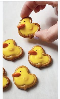 a person is holding some cookies with yellow icing on them and there are little rubber ducks in the middle