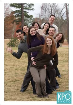 a group of people posing for a photo in a field with trees and grass behind them