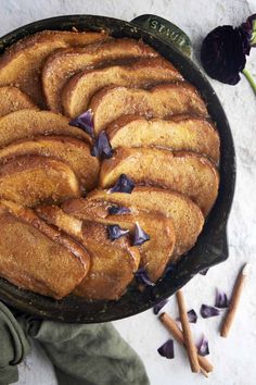 a pan filled with food sitting on top of a table next to some purple flowers