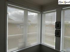 two windows with white blinds in the corner of a room, one is open and the other is closed