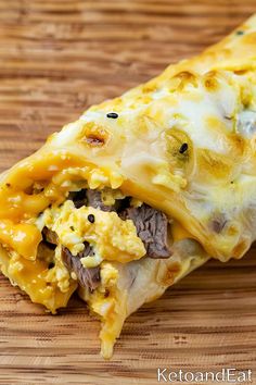 an enchilada with meat and cheese on a cutting board