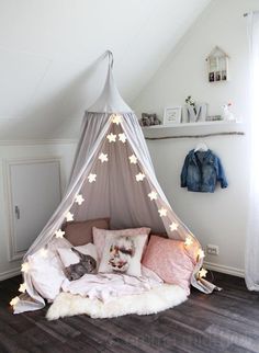 a bed that has some lights on it in the corner of a room with wood flooring