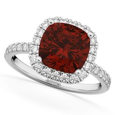 a cushion shaped red diamond surrounded by white diamonds in a halo setting on an 18k white gold ring