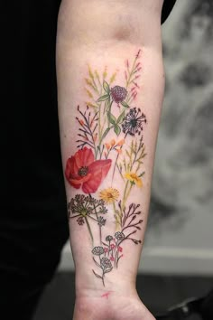 a woman's arm with flowers on it and a tattoo that says wildflowers