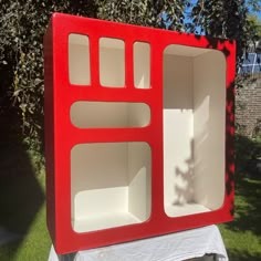 a red and white box sitting on top of a table in front of a tree