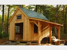 a small wooden shed in the woods with a metal roof on it's side