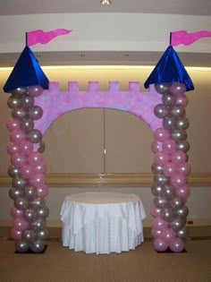 an arch made out of balloons with pink castle on top