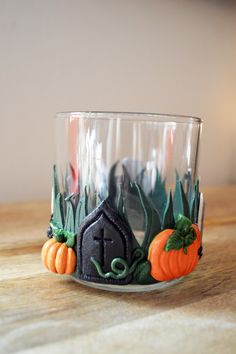 a glass with some decorations on it sitting on top of a wooden table next to a candle holder