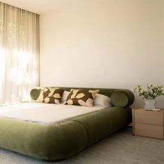 a large bed sitting in the middle of a bedroom next to a window with curtains