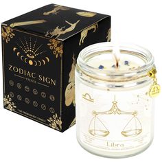 the zodiac sign candle is in front of a black box with gold foil on it