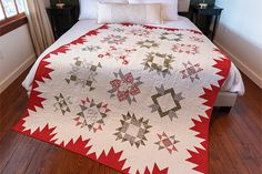 a bed with a red and white quilt on it