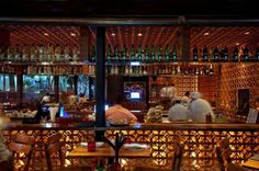 people sitting at tables in a restaurant with lots of bottles on the wall behind them