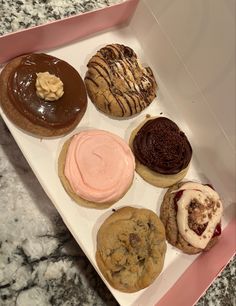 a box filled with lots of different types of doughnuts on top of a table