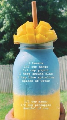 a hand holding a blue and yellow mason jar with pineapple slices on the top