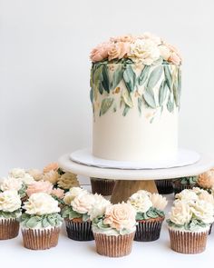 cupcakes with flowers on them are sitting in front of a cake