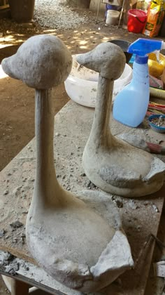 two cement birds sitting on top of a table