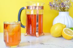 two pitchers of lemonade sit on a marble counter top next to some lemons