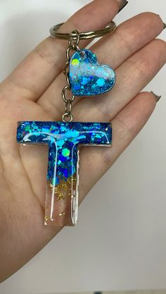 a hand holding a cross shaped keychain with blue and green designs on it