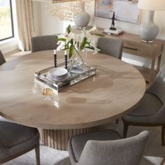 a dining room table with chairs around it and a vase filled with flowers on top