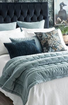 a bed with blue and white comforters, pillows and blankets on top of it