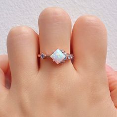 a woman's hand holding a ring with an opalite and diamonds on it