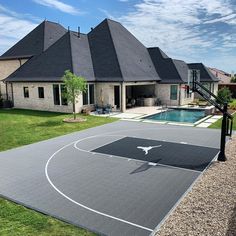 an outdoor basketball court in front of a house with a pool on the other side