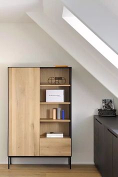 a book shelf with books on top of it in a room under a slanted roof