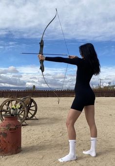 a woman with long black hair is holding a bow and arrow