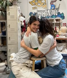 two women hugging each other while sitting on a chair