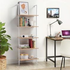 a computer desk with a laptop on top of it next to a potted plant