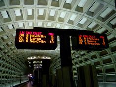 an underground subway station with electronic signs