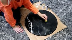 a woman sitting on the floor with her hands on a round black piece of paper