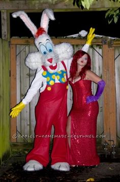 two people dressed up in costumes standing next to each other near a fence and tree