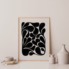 a black and white art piece sitting on top of a table next to vases