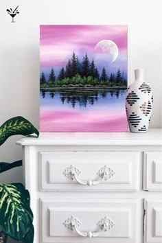 a painting on a dresser next to a potted plant and a vase with a pine tree in it