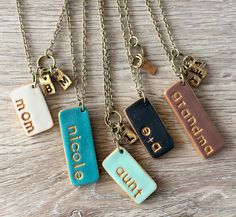 four different colored tags with the word love on them hanging from gold chain necklaces